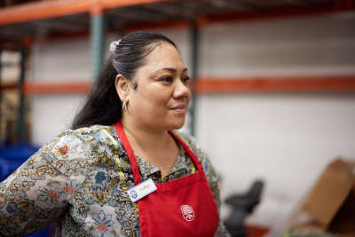 Thrift store worker looks off in the distance. She is wearing a red apron.